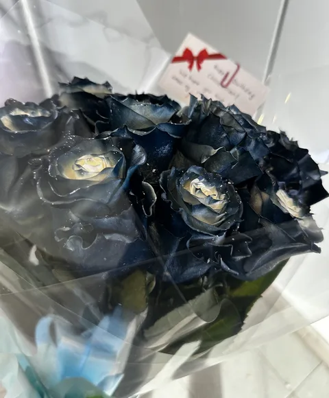 Black and gold dyed roses in clear wrap with a red bow