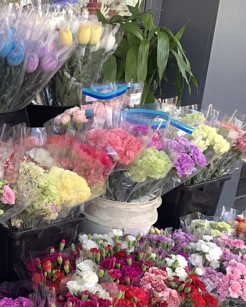 Buckets of wrapped carnations, lisianthus and tulips at the shop