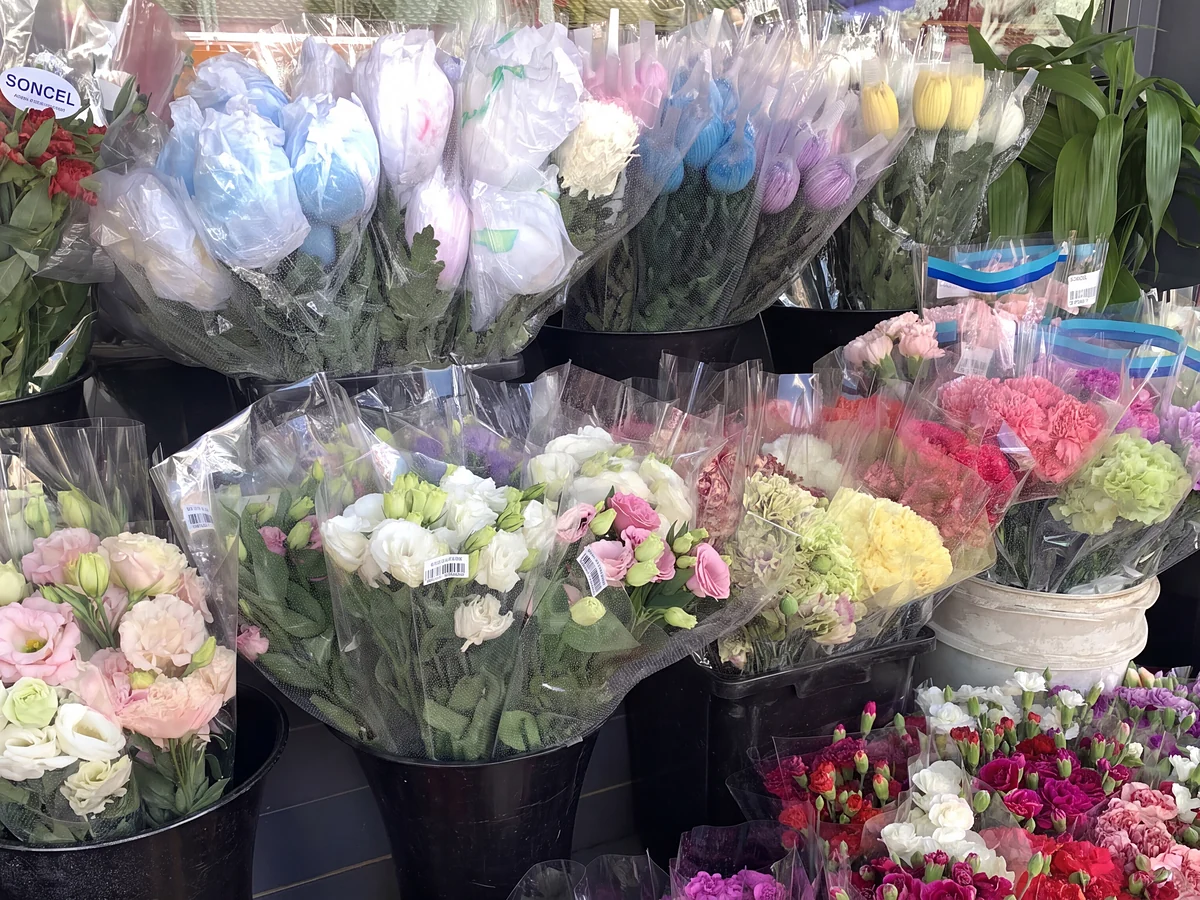 Buckets of wrapped lisianthus, carnations and tulips at the shop