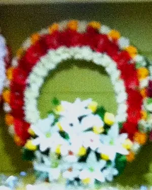 A round wreath of red and white carnations with white lilies in the middle